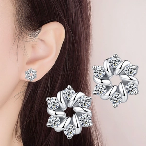 Sparkling silver flower stud earrings with zirconia stones worn by a woman