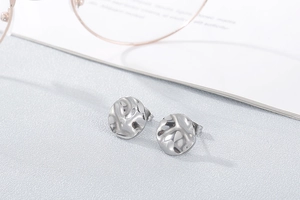 Detailed view of silver stud earrings with an irregular hammered texture and metallic finish