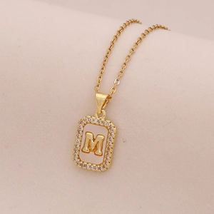 Détail du collier en or 18K avec initiale M sur nacre et cristaux étincelants
