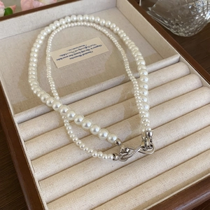 Detail view of double-layered pearl necklace with silver clasp in a jewelry display tray