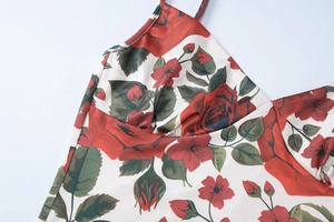 Detail shot of white floral V-neck dress featuring red rose and green leaf patterns