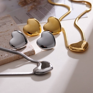 Artistic close-up of gold and silver heart-shaped jewelry set with snake chains on stone