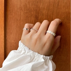 925 silver daisy ring set with wavy and beaded bands shown on hand with wooden background