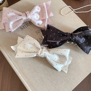 Elegant satin polka dot bow hair clips in pink beige and brown on vintage books