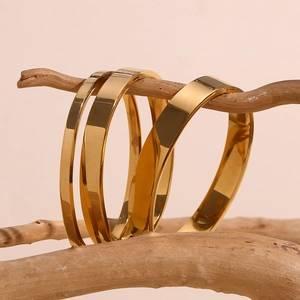 Close-up of three different widths of 18K gold plated stainless steel bangles on wood