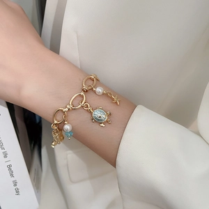 Detailed shot of golden marine bracelet featuring starfish, turtle and pearl charms