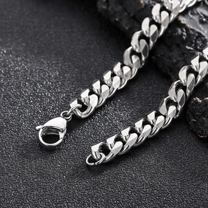 Close-up of silver stainless steel Cuban link chain with lobster clasp on dark stone