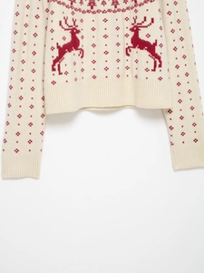 Detailed close-up of knit texture and red reindeer jacquard pattern on cream sweater