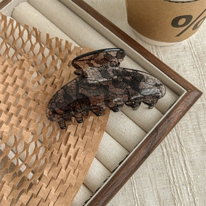 Detail of a large brown hair claw clip with vintage black lace mesh pattern on velvet