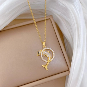 Macro view of gold dolphin pendant jumping through ring with sparkling crystal pave stones