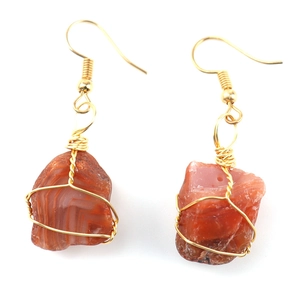 Detail of handmade wire wrapped earrings featuring raw red agate stones with golden finish
