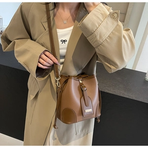 Close-up of brown lychee grain leather bucket bag with drawstring and adjustable strap