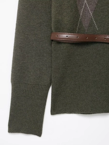 Dettaglio del cardigan in maglia verde scuro con motivo a rombi e cintura in cuoio