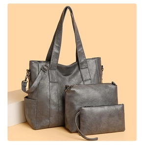 Detailed view of gray three-piece set featuring large tote, handbag, and clutch bags