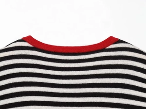 Close-up of knit sweater crew neck with black white stripes and red trim detail