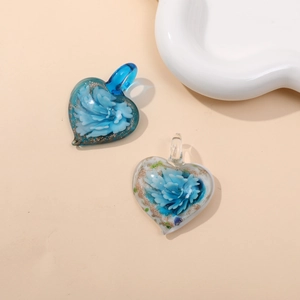 Macro detail of heart-shaped glass pendants with internal blue flowers and gold foil accents