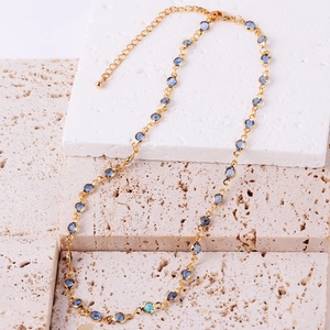 Detail of adjustable gold-plated chain necklace featuring vibrant blue zircon gemstones
