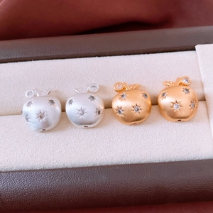 Detail of 18K gold and silver brushed apple stud earrings with star-set cubic zirconia