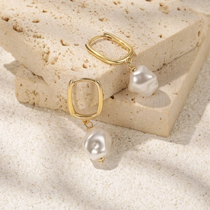 Detailed close-up of gold pearl earrings on a natural textured stone background