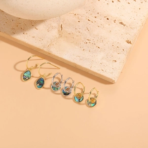 Macro detail of S925 silver and gold earrings with iridescent abalone shell pendants