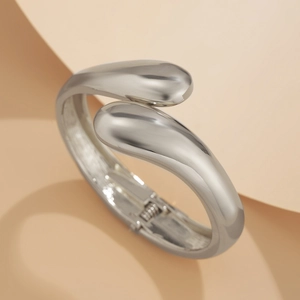 Detailed macro view of silver teardrop open cuff bracelet with polished metal finish