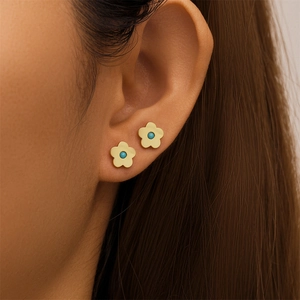 Detailed close-up of S925 silver flower stud earring with turquoise bead on human ear