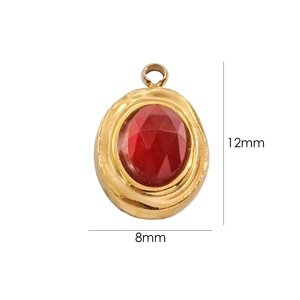 Macro shot of 12mm x 8mm oval gold pendant with a faceted red gemstone center