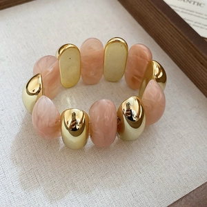 Detail of marble resin beads and gold metal segments on a stretch fashion bracelet