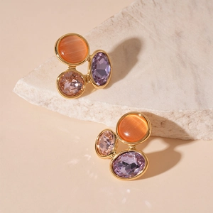 Vue macro de boucles d'oreilles en pierre œil de chat orange et violette sur marbre