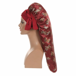 Close-up of red satin bonnet featuring golden butterfly prints and adjustable ribbons