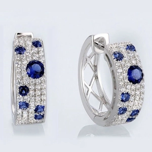 Polished silver earrings with blue stones and white zircon crystals on grey background