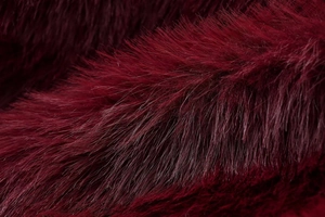 Detailed close-up of dark wine red faux fur texture with long plush fibers and soft gloss