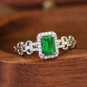 Dettaglio dell'anello con pietra verde taglio smeraldo, pavé di diamanti e maglia a catena