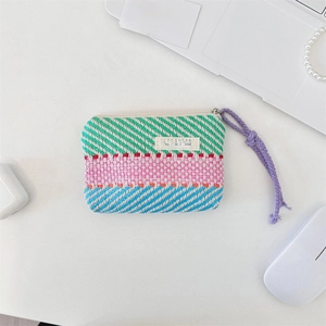 Detail of colorful striped woven makeup bag with Sozakka tag and purple zipper pull