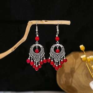 Boucles d'oreilles bohèmes argentées avec perles rouges sur une branche en bois