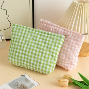 Close-up of quilted gingham makeup bags in soft pink and green with metal zipper detail