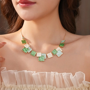 Détail du collier à pendentifs carrés en émail coloré porté avec une chaîne dorée