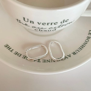 French style S925 sterling silver oval hoop earrings displayed on a white ceramic saucer