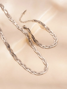 Detail of silver woven herringbone chain necklace and bracelet on beige satin background