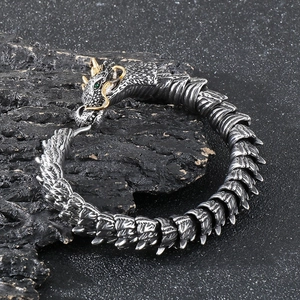 Macro detail of punk dragon bracelet with green gemstone eyes and silver scales