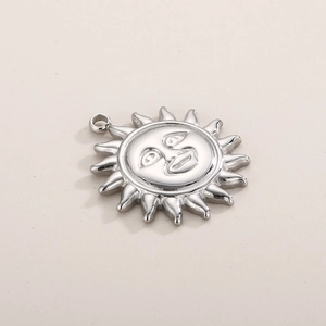 Macro shot of silver sun pendant charm with smiling face and polished metal rays