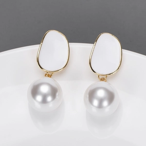 Détail de boucles d'oreilles en émail rose avec grands pendentifs perles blanches sur plateau