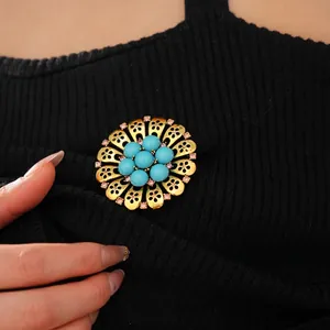Vintage style hollow floral brooch with blue beads and pink rhinestones on a black knit top
