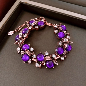 Detailansicht eines Vintage-Blumenarmbands mit violetten Cabochons und funkelnden Strasssteinen