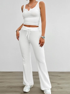 Detail of white yoga set featuring sleeveless crop top and flared drawstring trousers