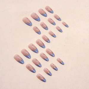 French almond press-on nails in nude pink with blue tips and gold star patterns