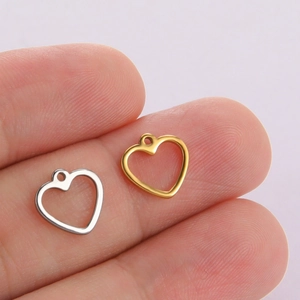 Gold and silver hollow heart pendants on fingers showing size for DIY jewelry