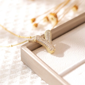 Macro shot of gold-plated 'Y' pendant with zircon pavé setting on a soft jewelry tray