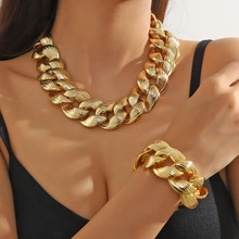 Close-up of a gold chunky chain necklace and bracelet set worn by a model