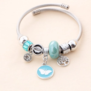 Macro shot of silver beaded bracelet featuring butterfly and tree of life charms